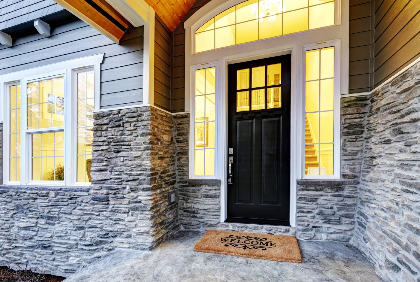 Stone and timber entry of an AXIS custom home lit at dusk