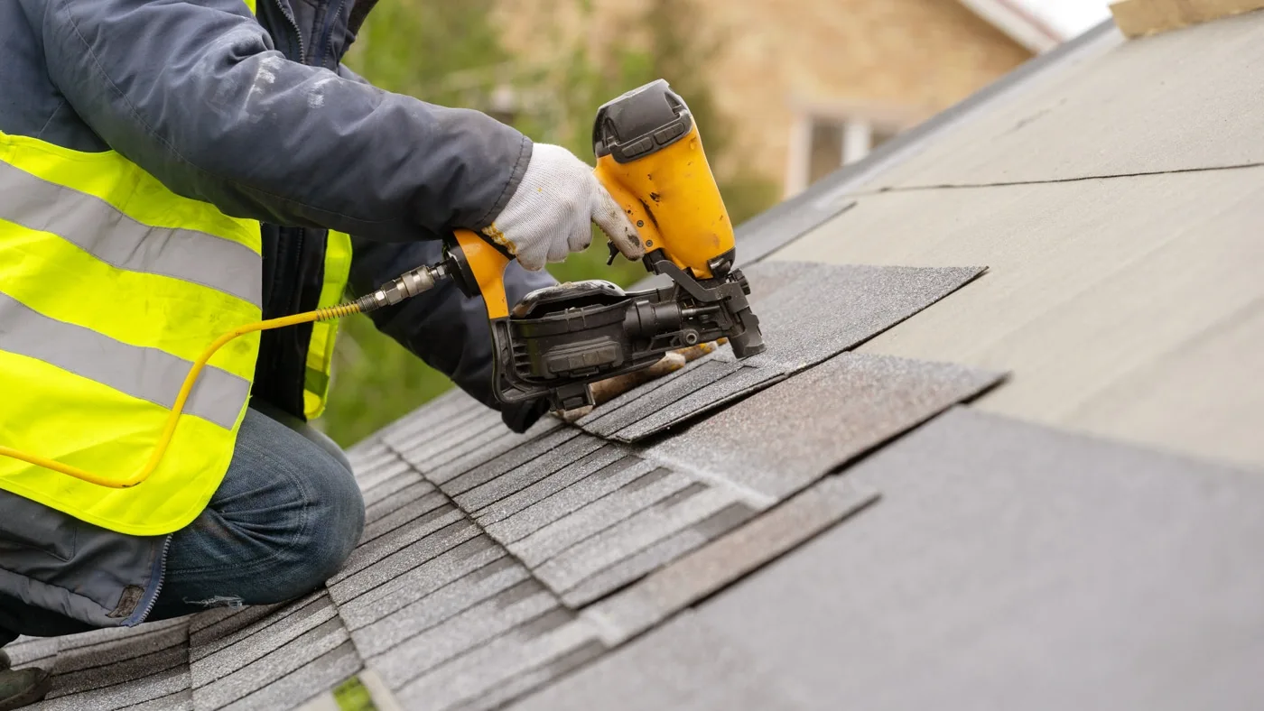 Roofer using a nail gun to fasten new shingles in Southwest Indiana